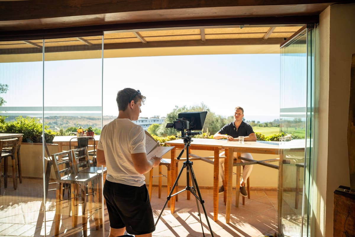 Opname op een terras in Spanje: cameraman achter het statief, de klant aan de bar in het zonlicht