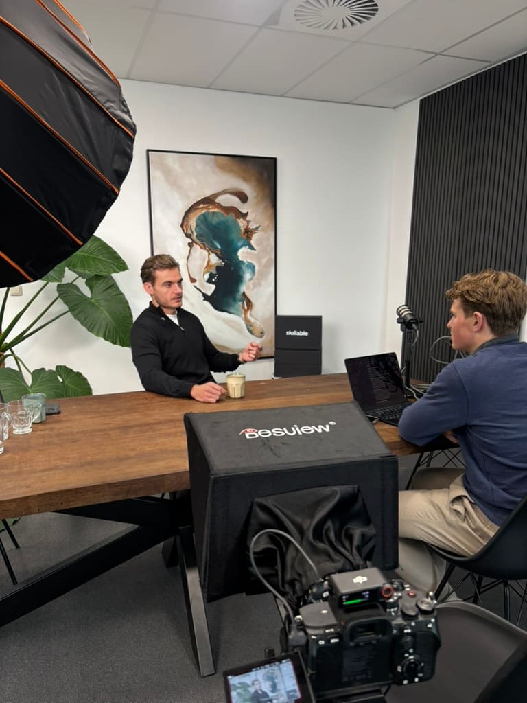 Interview aan een tafel op kantoor, softbox links en de camera op de voorgrond