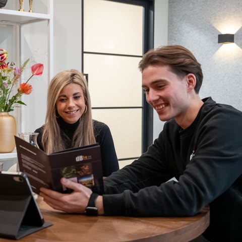 Twee medewerkers van DB-Akoestiek aan tafel met een brochure
