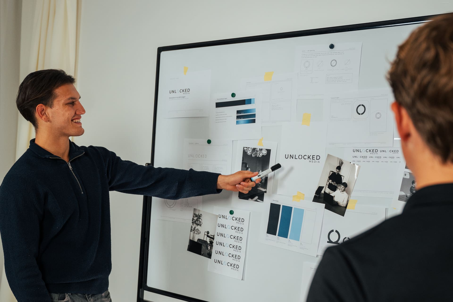 Twee oprichters van Unlocked Media bij een whiteboard met uitgeprinte contentformats en het merkpalet